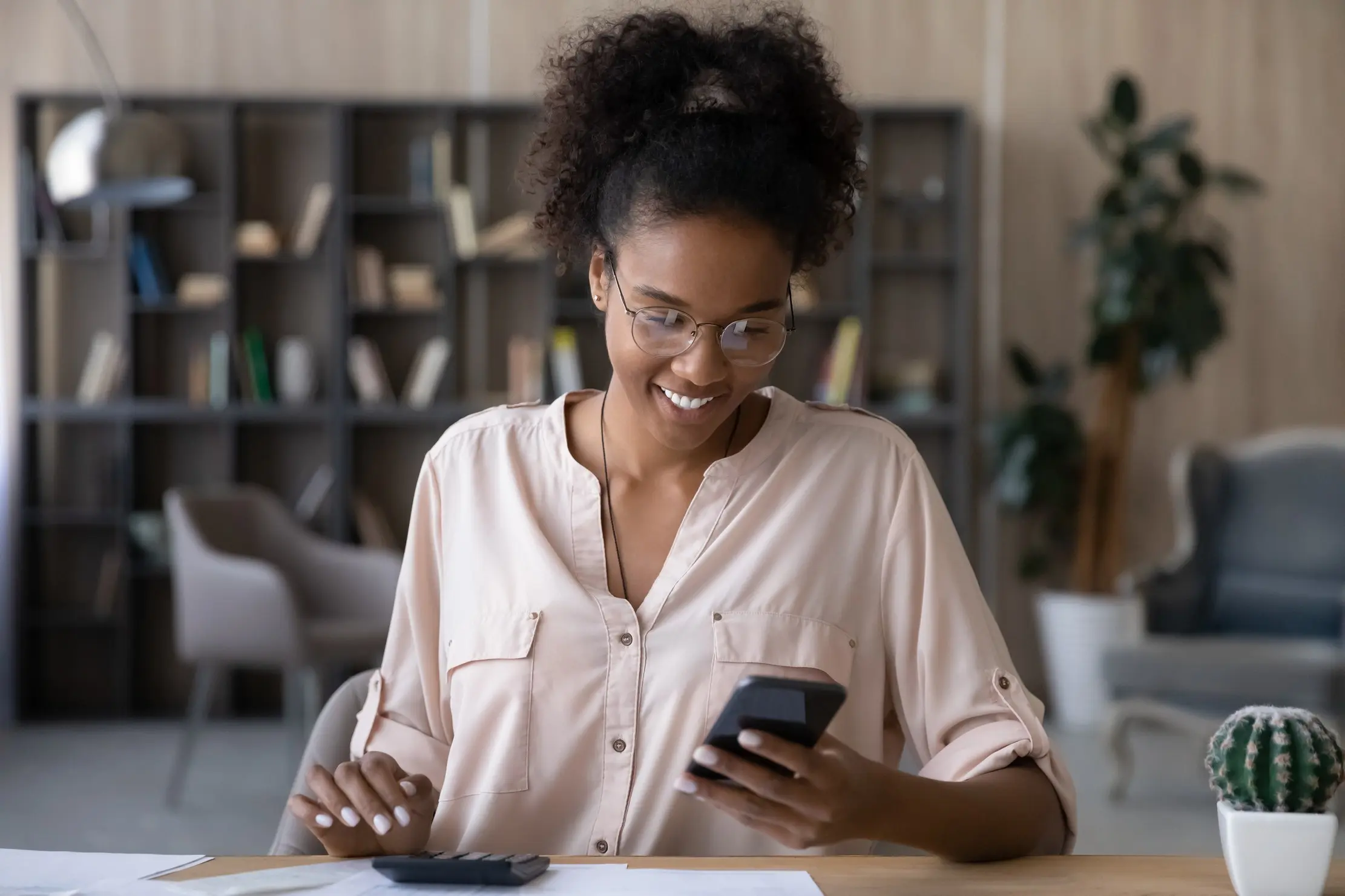 Shop manager checking a mobile payment and daily balance on a phone at a desk