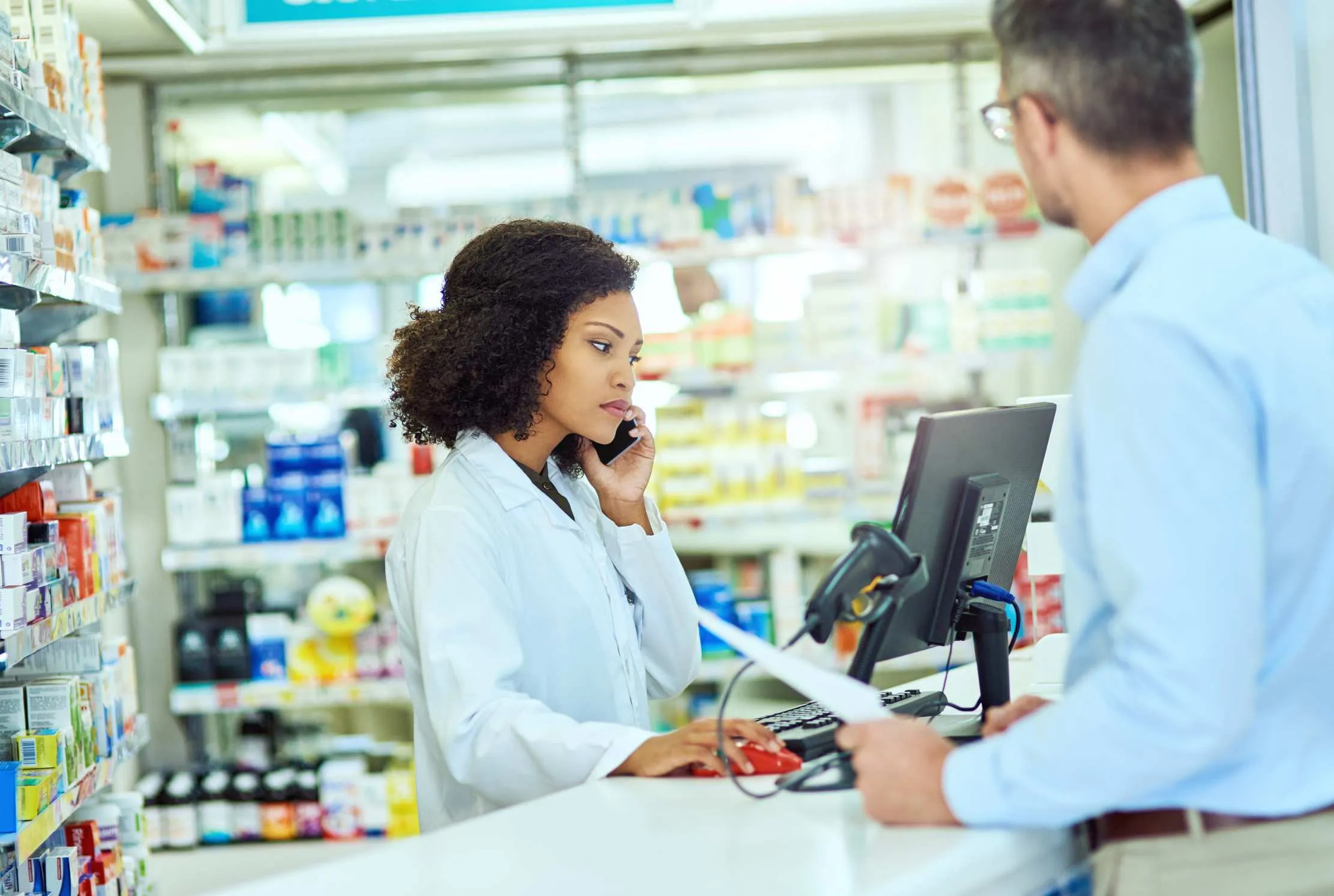Pharmacy team checking medicine stock and confirming a customer prescription order over the phone