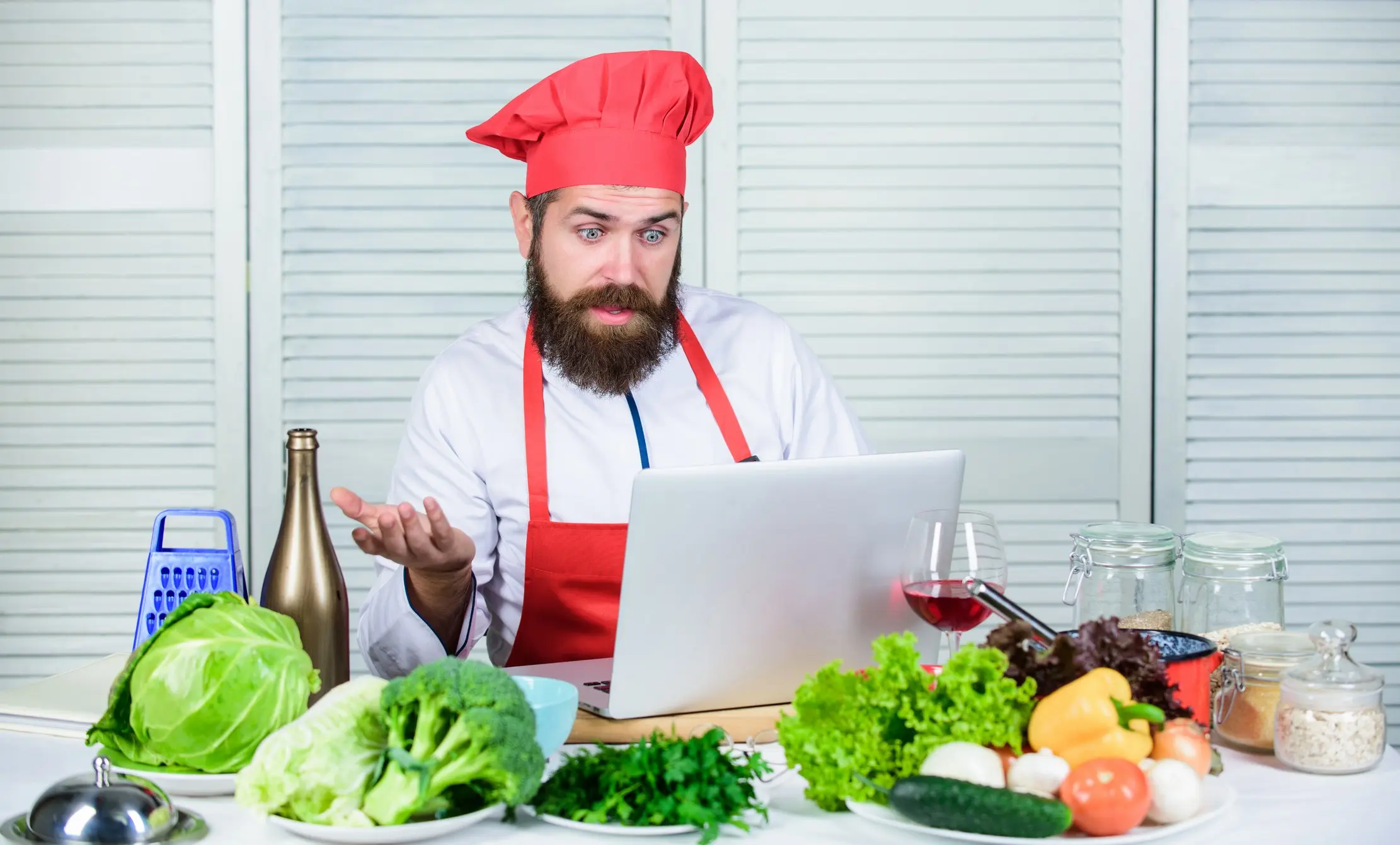 Chef comparing fresh ingredients with a recipe on a laptop