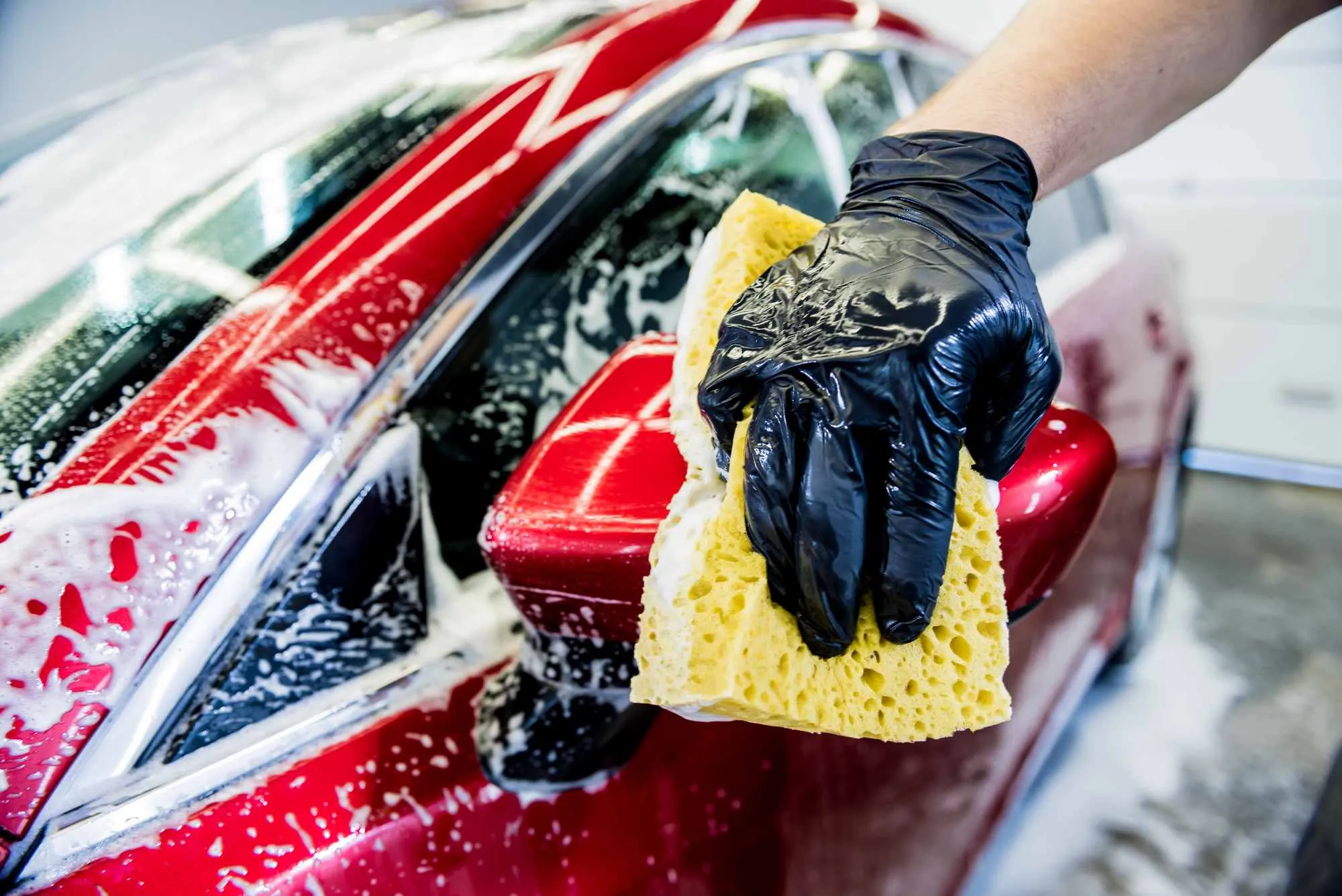 Car wash attendant cleaning a vehicle, representing wash packages and car accessory sales in Maduuka